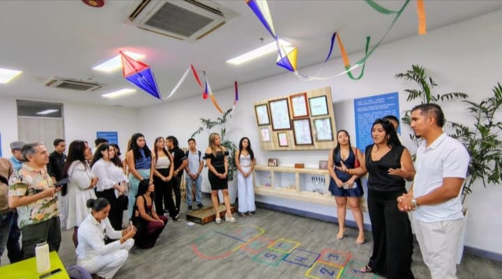 Estudiantes presentan una mesa con objetos y materiales relacionados con prácticas lúdicas tradicionales en Santa Marta.