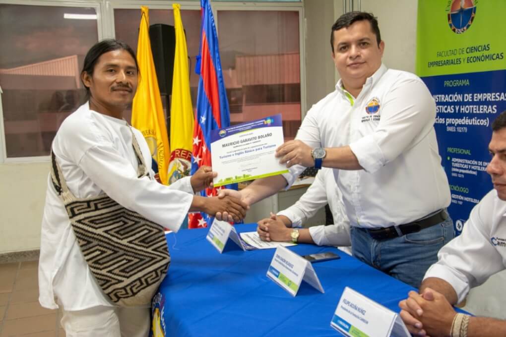 Jhonatan Mocote Nuvita de la etnia indígena Kogui recibe su certificado de capacitación en turismo e inglés de mano del Decano de la Facultad de Ciencias Empresariales y Económicas, magíster Edwin Chacón Velásquez.