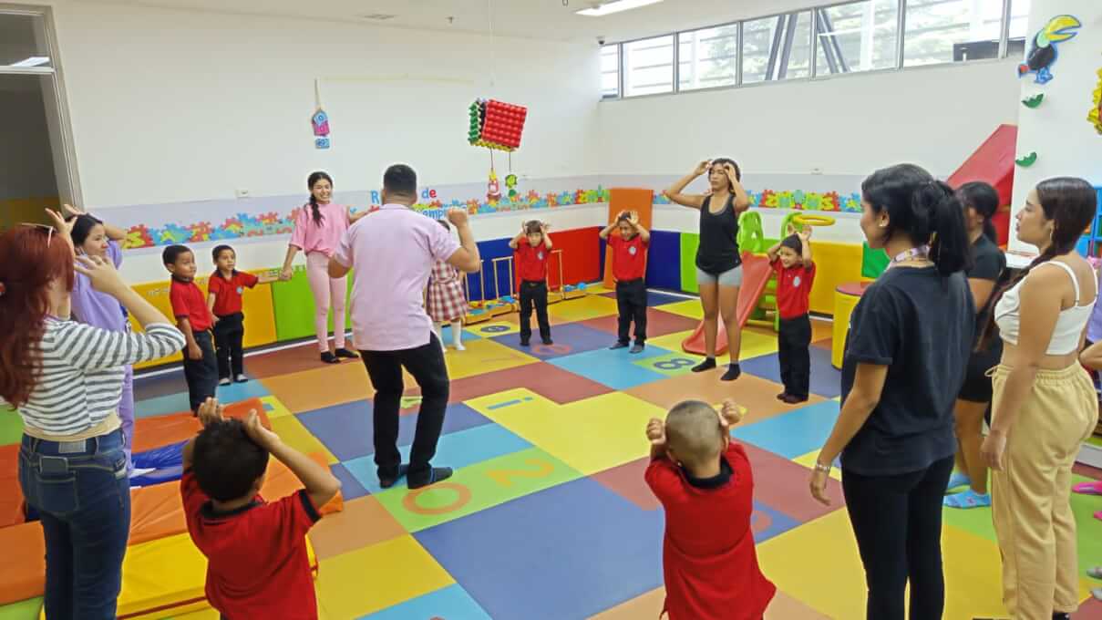 Niños y docentes participan en una actividad lúdica en un ambiente educativo colorido y dinámico
